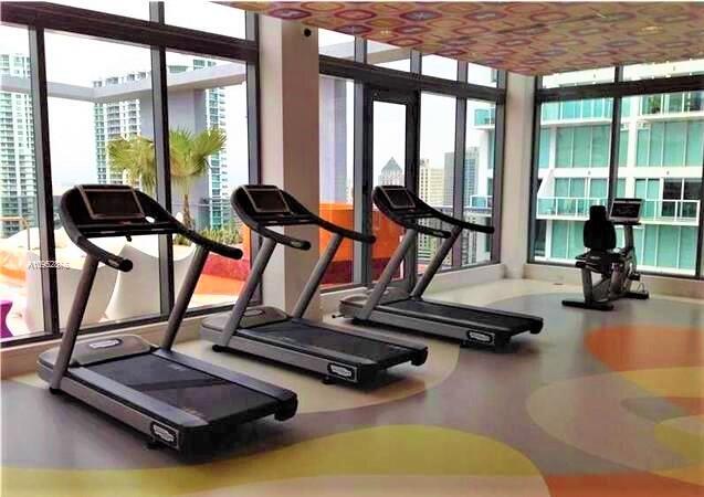 31 Southeast 6th Street, Unit 602 Miami, FL 33131 - Photo 25 of 39 a room with gym equipment and floor to ceiling windows