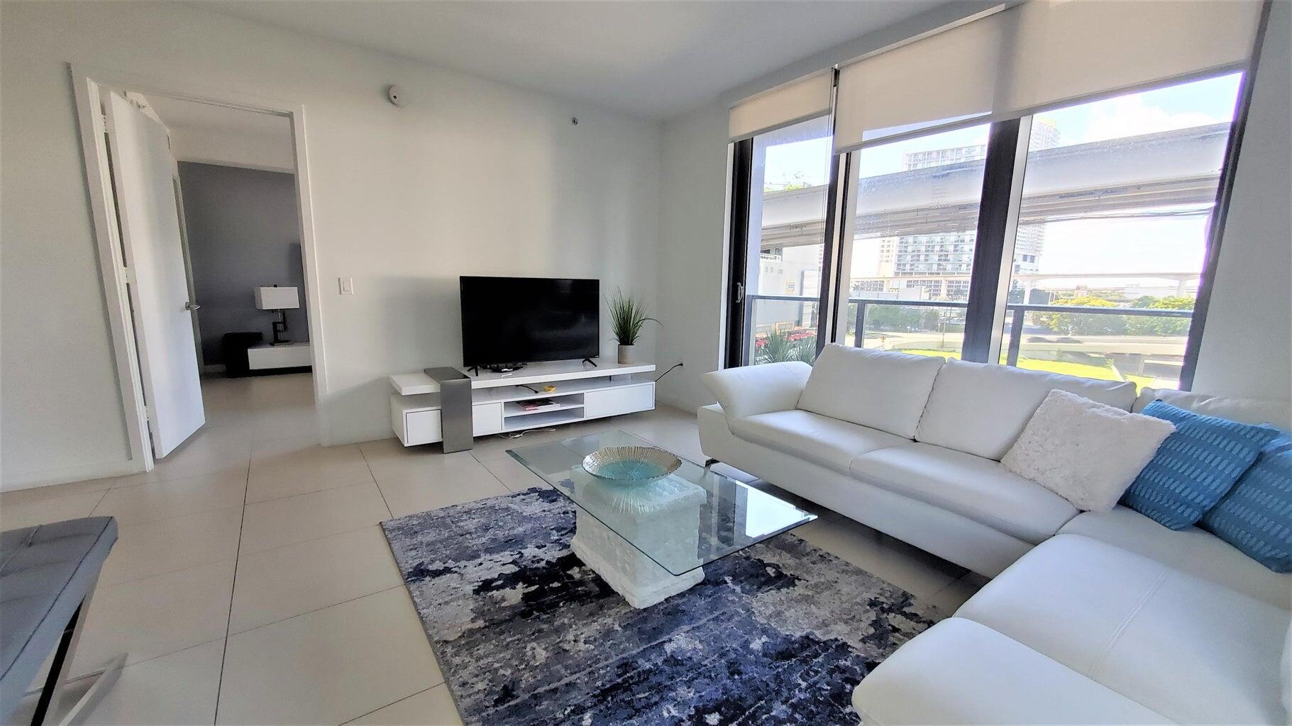 31 Southeast 6th Street, Unit 602 Miami, FL 33131 - Photo 3 of 39 a living room with furniture and a flat screen tv