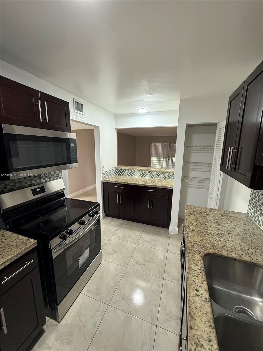 4121 Stirling Road, Unit 402 Dania Beach, FL 33314 - Photo 3 of 10 a kitchen with granite countertop a stove and a sink
