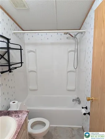 a bathroom with a granite countertop bathtub shower sink vanity and toilet