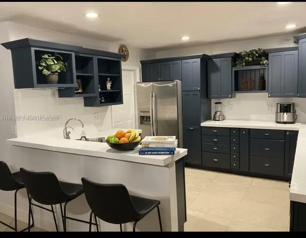 a kitchen with stainless steel appliances kitchen island granite countertop a refrigerator and a stove top oven