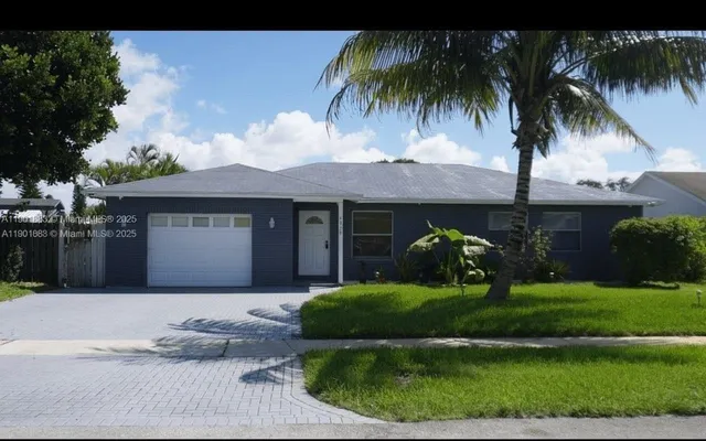 a front view of a house with a garden and palm trees
