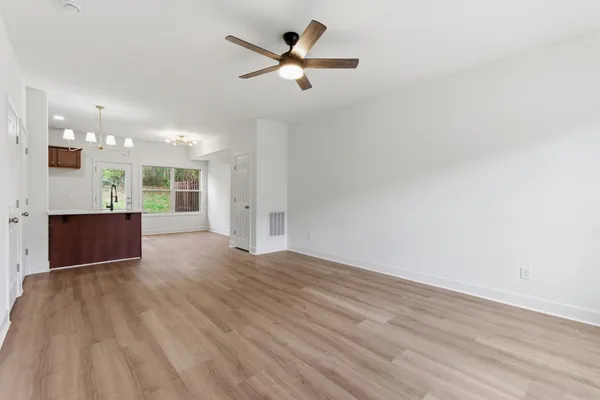 an empty room with wooden floor and a ceiling fan