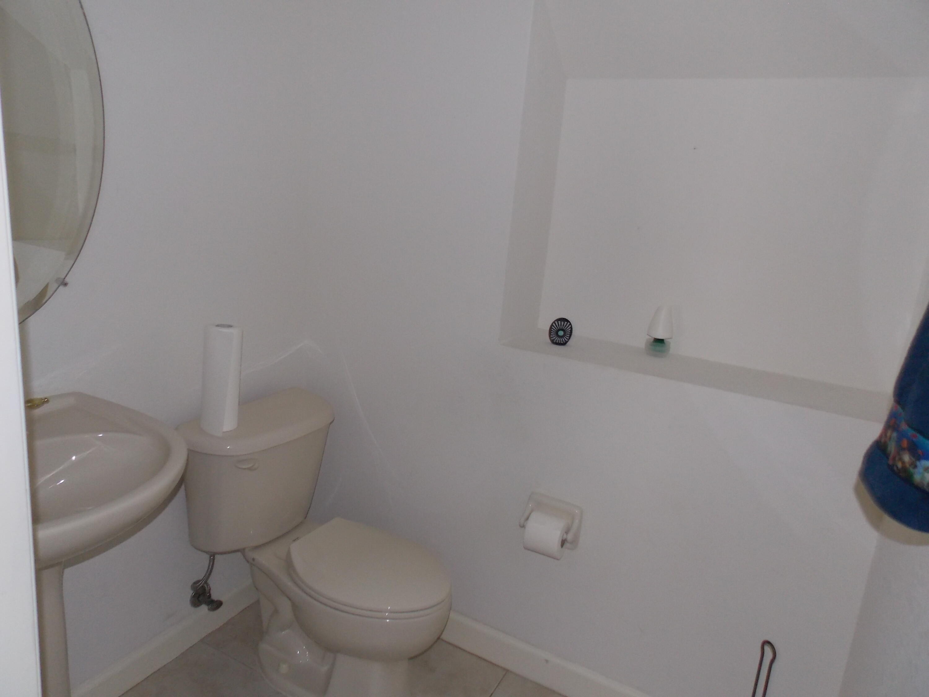 323 Northwest Sheffield Circle Port St. Lucie, FL 34983 - Photo 16 of 31 a white toilet sitting next to a white sink and vanity