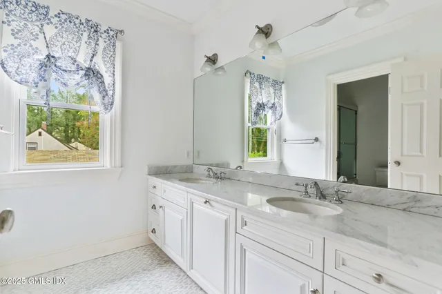 a bathroom with a granite countertop sink mirror and window