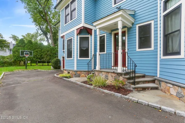 a view of brick house with a yard and large tree