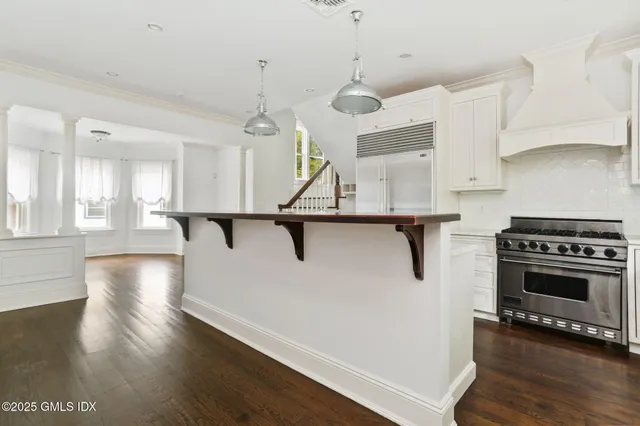 a kitchen with stainless steel appliances granite countertop a refrigerator a stove a sink dishwasher and a dining table with wooden floor