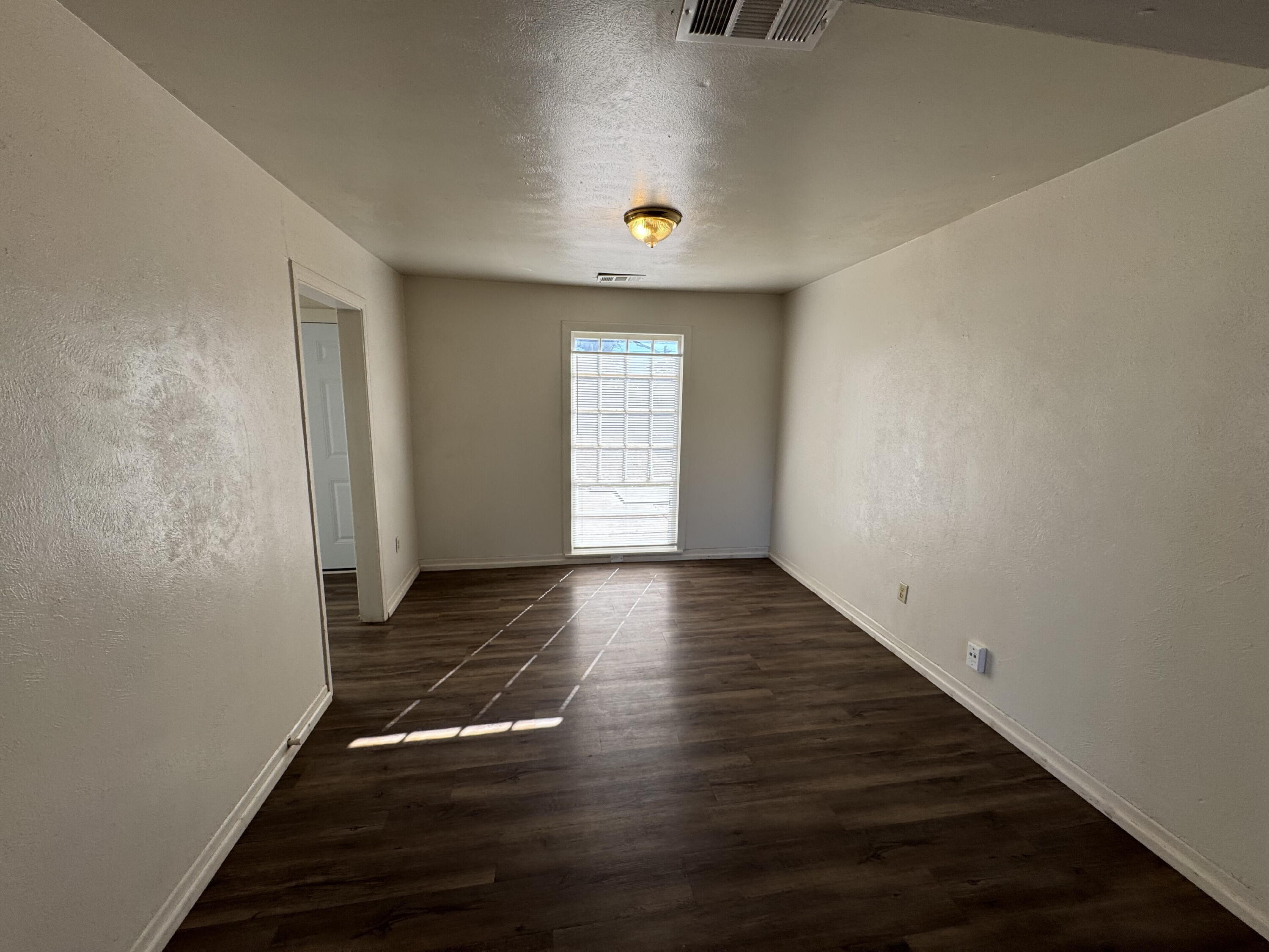 2119 32nd Street Lubbock, TX 79411 - Photo 3 of 9 a view of an empty room with wooden floor and a window
