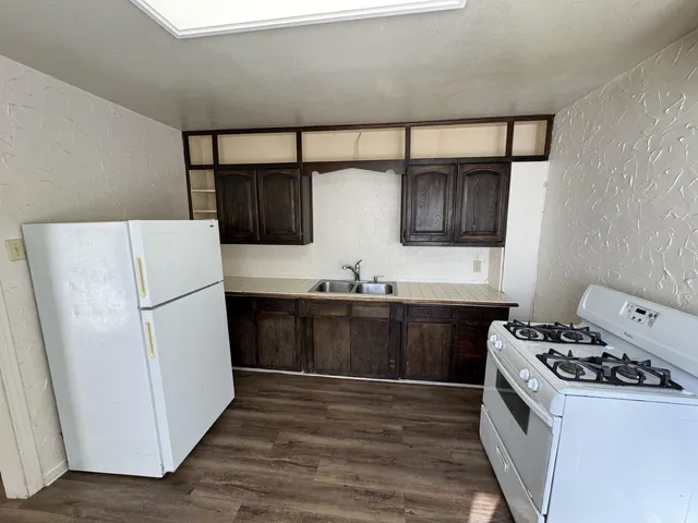 a kitchen with stainless steel appliances a refrigerator a sink and wooden cabinets