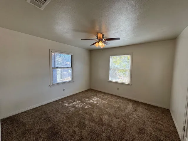 an empty room with windows and fan