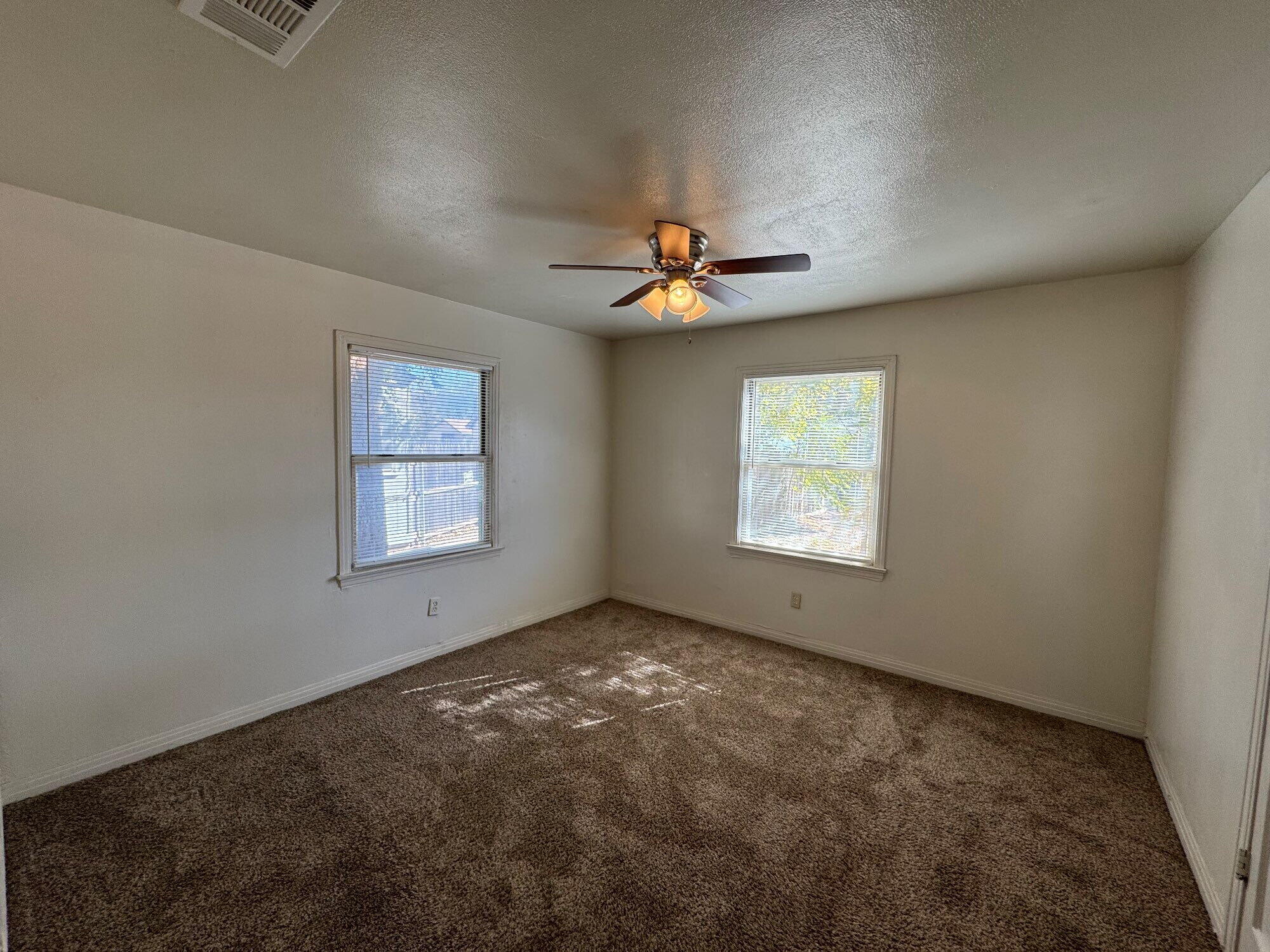 2119 32nd Street Lubbock, TX 79411 - Photo 9 of 9 an empty room with windows and fan