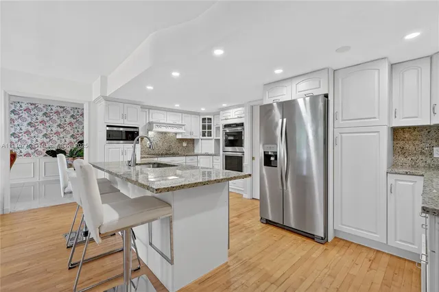 a kitchen with stainless steel appliances granite countertop a refrigerator and a stove top oven