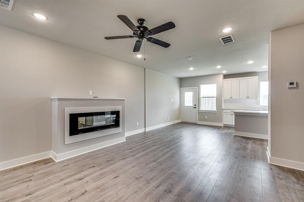 912 Cooksey Court, Unit B Grandview, TX 76050 - Photo 26 of 30 an empty room with wooden floor a ceiling fan a fireplace and windows