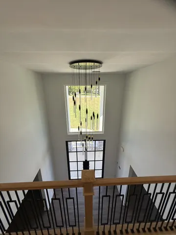 a view of a hallway with wooden floor and chandelier