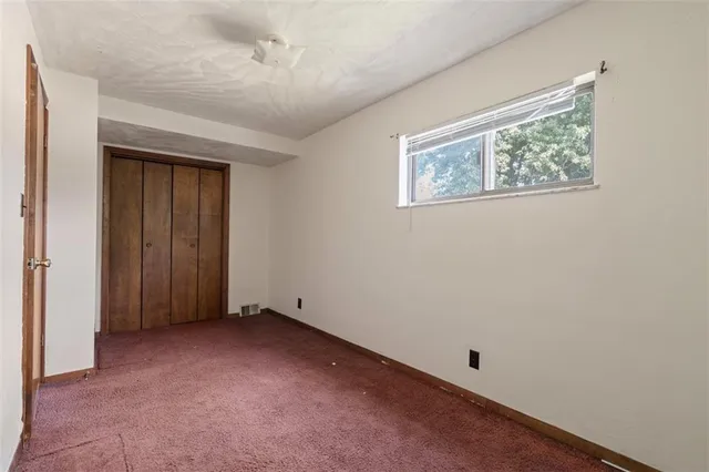 an empty room with a ceiling fan and a window