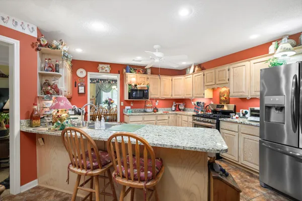 a kitchen with stainless steel appliances granite countertop a table chairs and a refrigerator