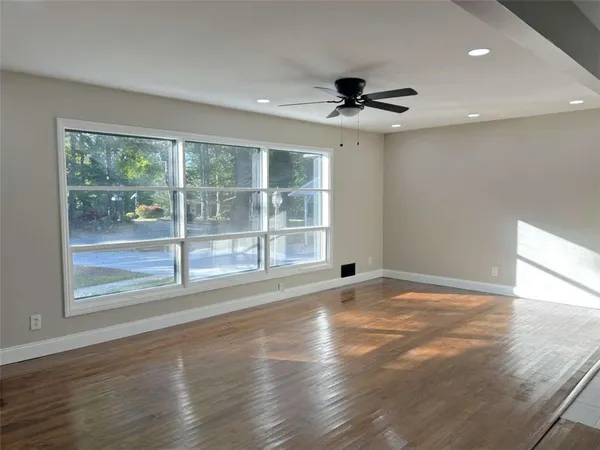 a view of an empty room with a window and wooden floor