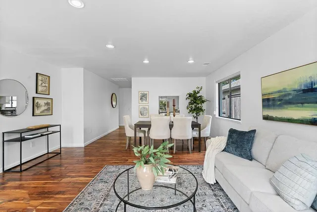 a kitchen with granite countertop a stove top oven a sink dishwasher a dining table and chairs with wooden floor