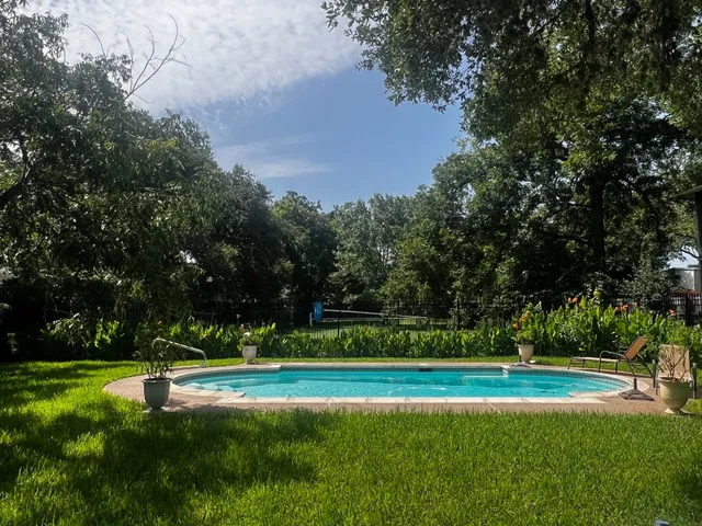 a view of a swimming pool with lawn chairs under an umbrella