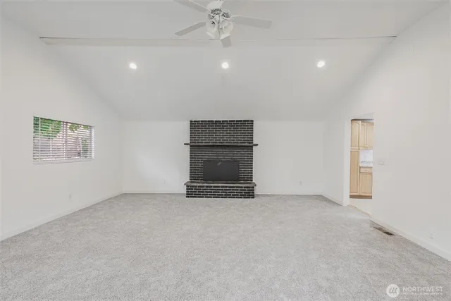 an empty room with a fireplace and a chandelier fan