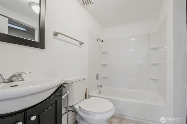 a bathroom with a bathtub shower sink mirror vanity and toilet