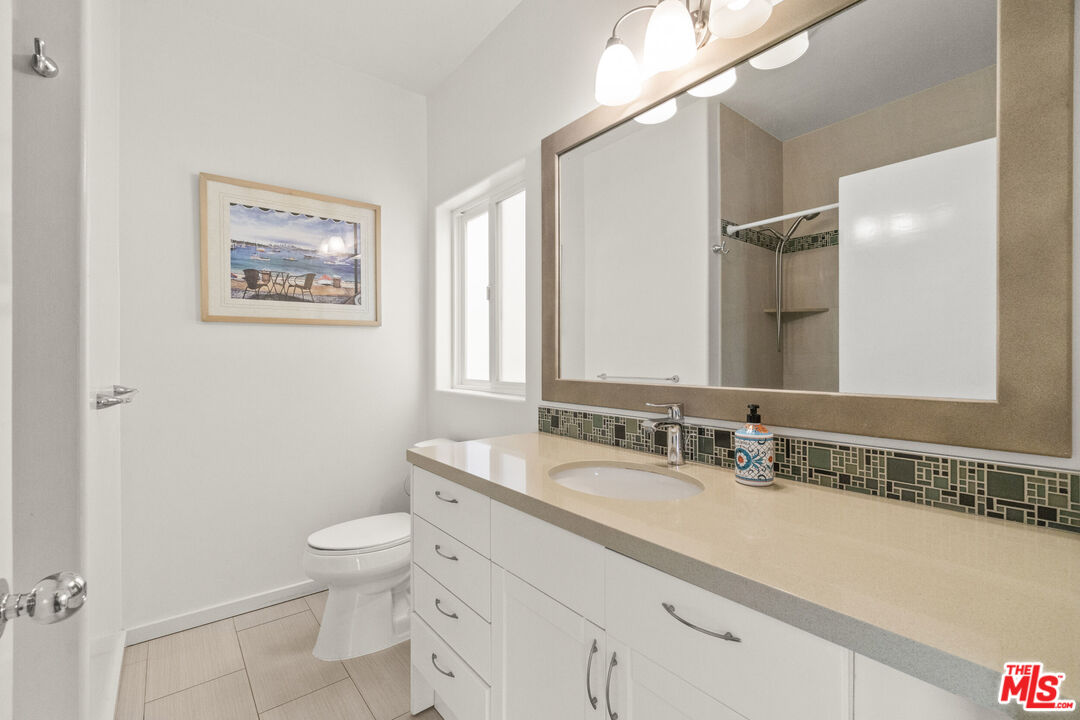 123 Galleon Street, Unit B Marina del Rey, CA 90292 - Photo 27 of 43 a bathroom with a granite countertop toilet sink and a mirror