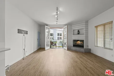 a view of an empty room with wooden floor fireplace and a window