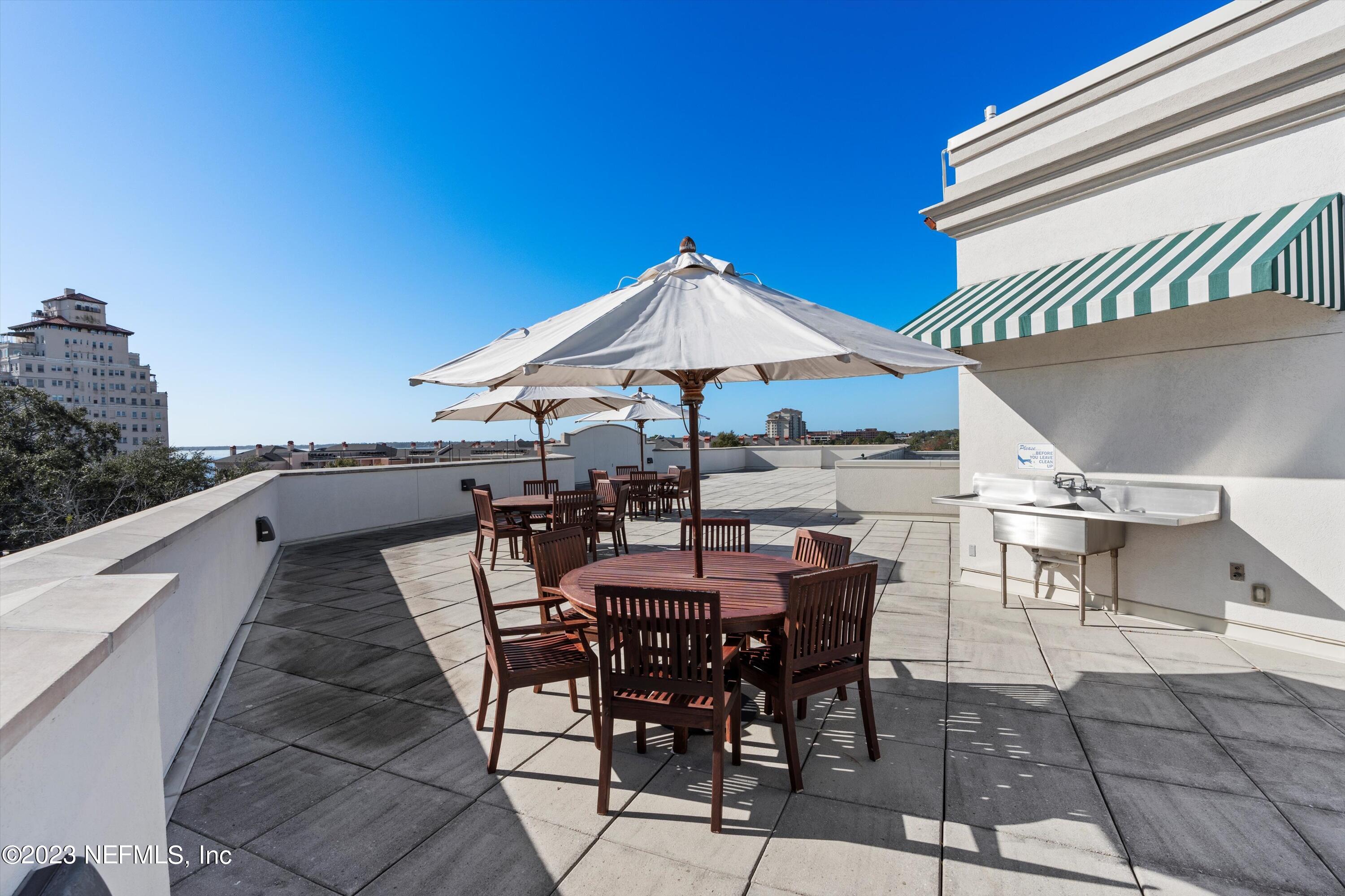 1661 Riverside Avenue, Unit 211 Jacksonville, FL 32204 - Photo 23 of 32 a view of a roof deck with table and chairs under an umbrella with a barbeque grill