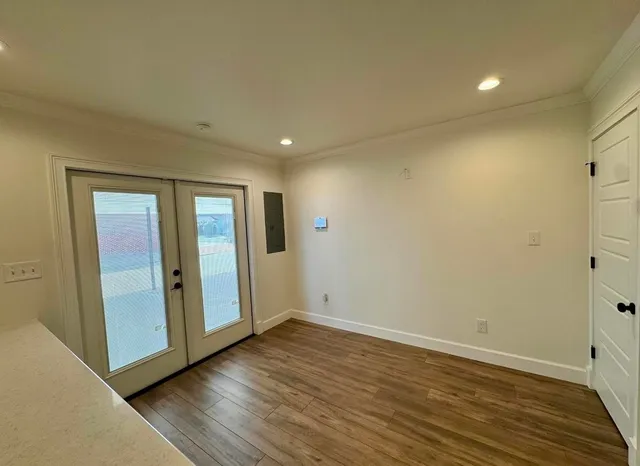 a view of an empty room with wooden floor and closet