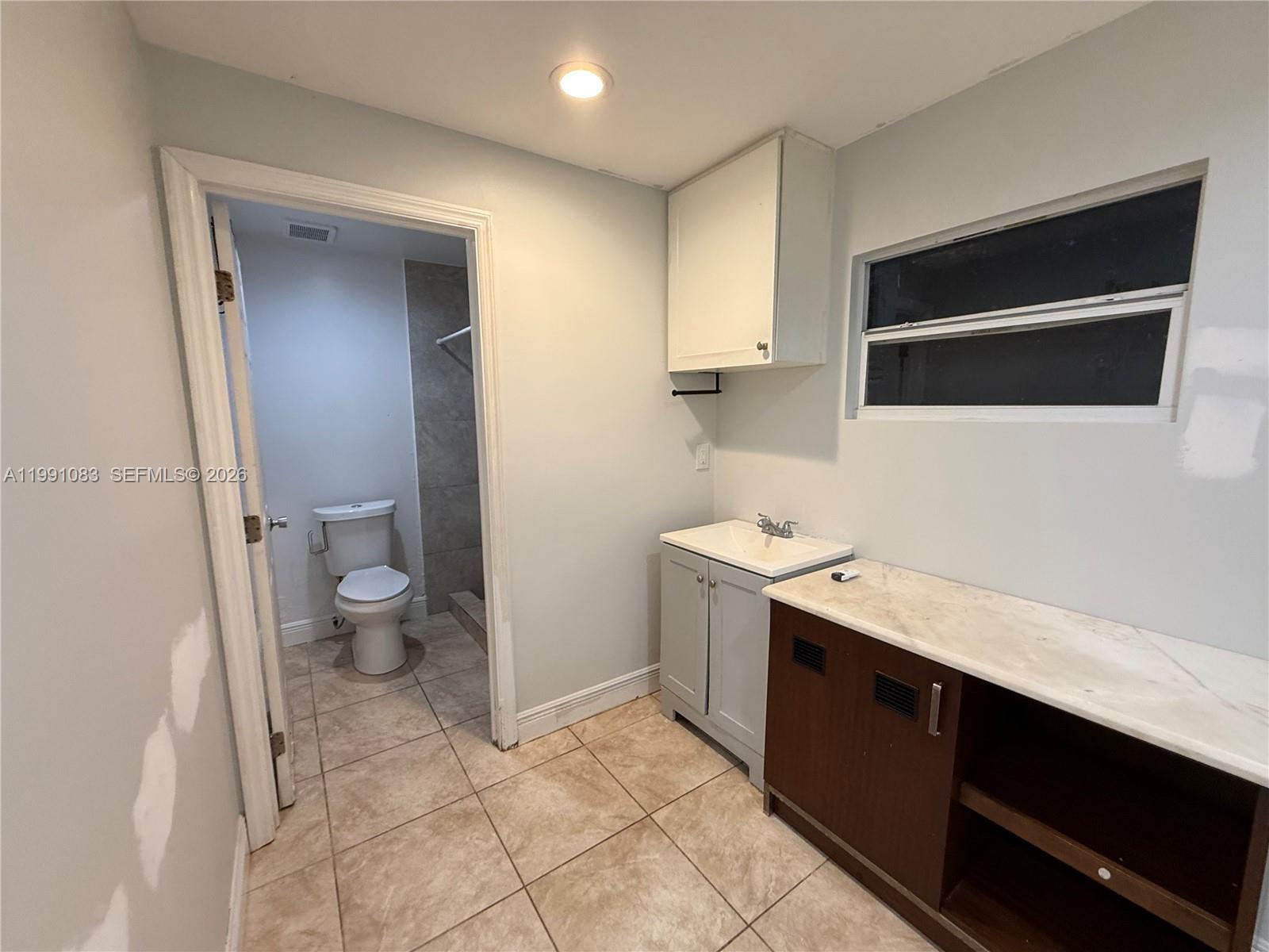 5488 Fearnley Road Lake Worth, FL 33467 - Photo 28 of 40 a utility room with a sink a toilet and cabinets