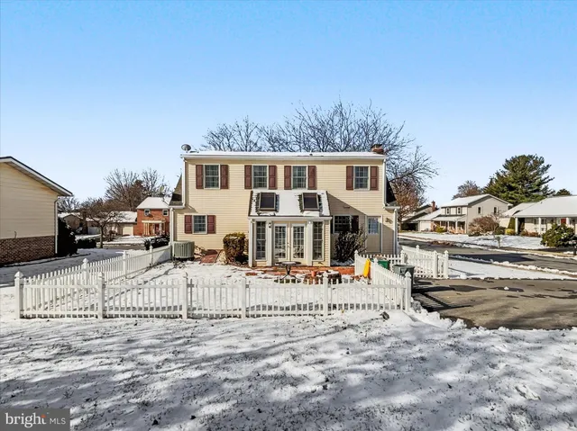a view of a white house with wooden fence next to a road