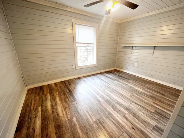 a view of empty room with wooden floor and fan