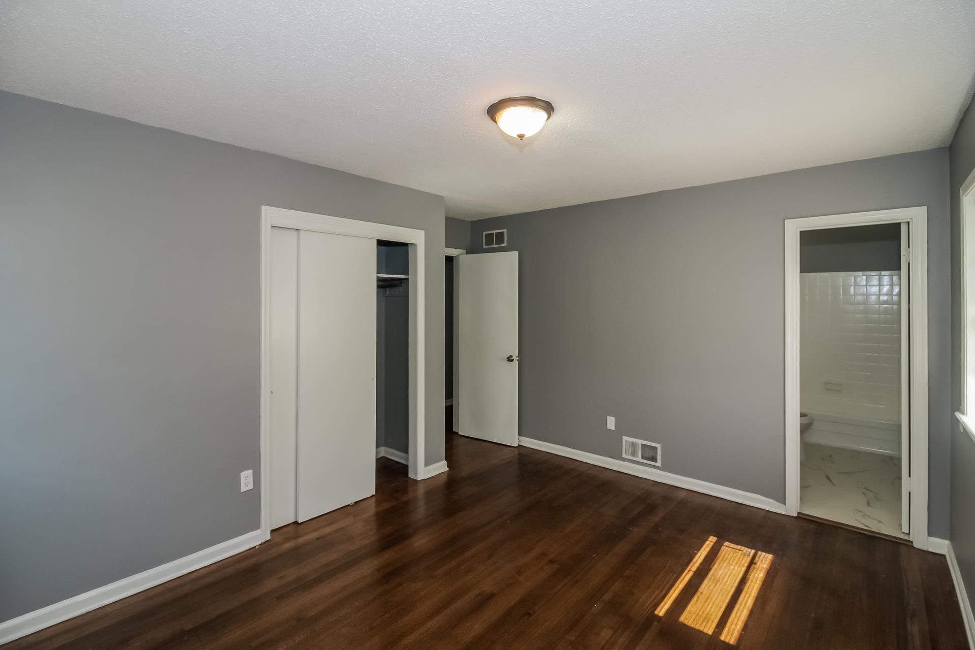 4559 Cottonwood Road Memphis, TN 38118 - Photo 14 of 16 Unfurnished bedroom with a closet, dark wood finished floors, and connected bathroom