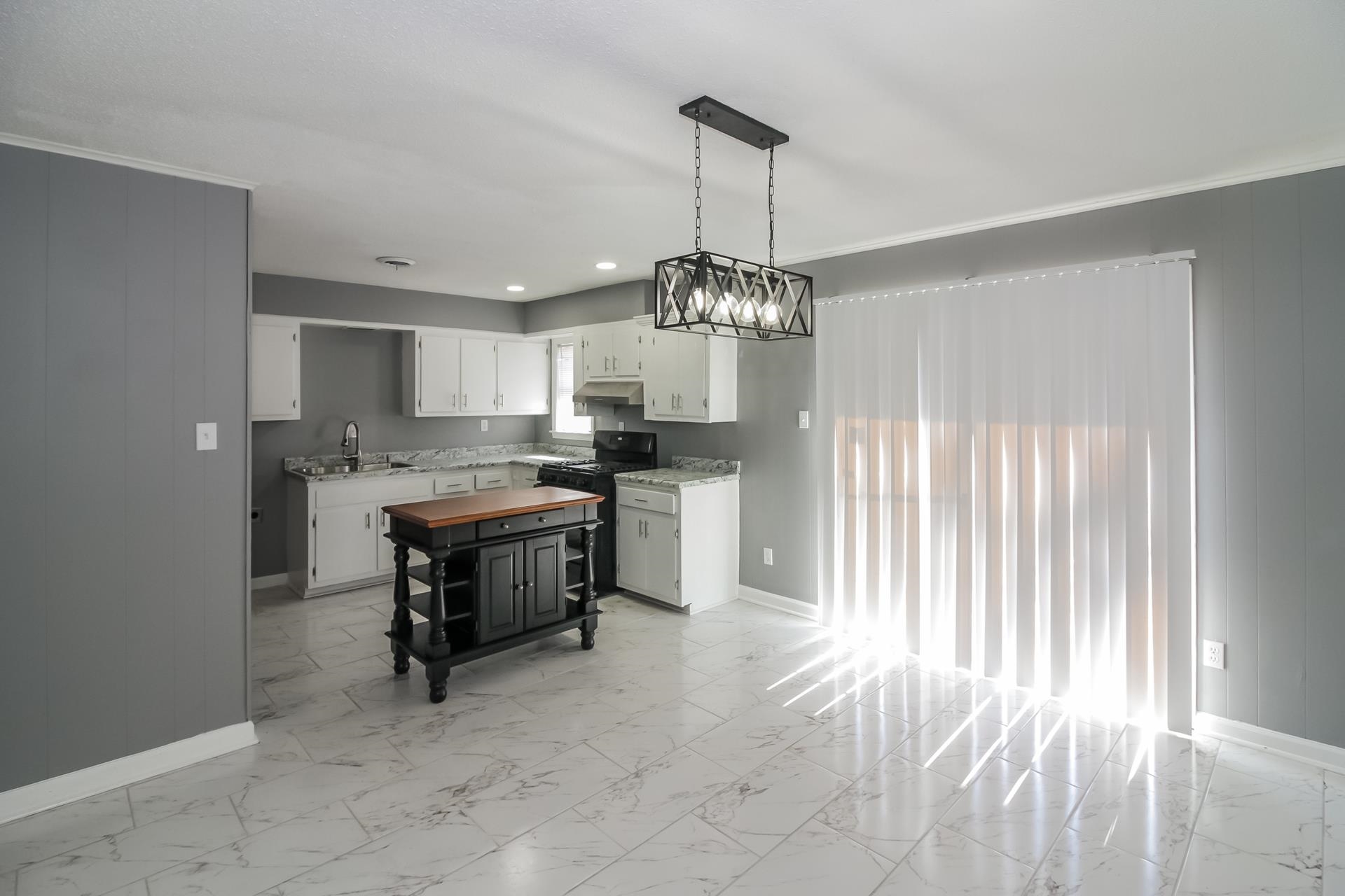 4559 Cottonwood Road Memphis, TN 38118 - Photo 3 of 16 Kitchen with white cabinets, black gas stove, wood walls, pendant lighting, and recessed lighting