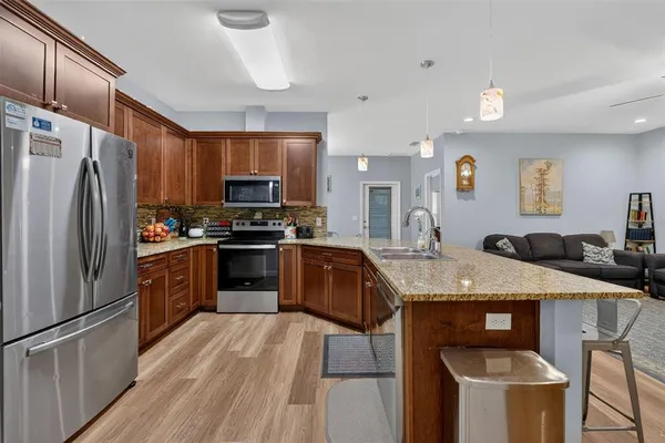 a kitchen with granite countertop a refrigerator a stove a sink a oven with a dining table and chairs