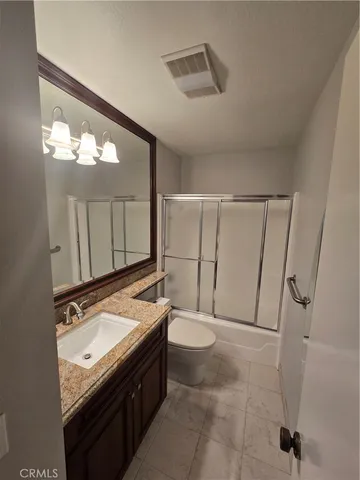 a bathroom with a granite countertop sink toilet and mirror