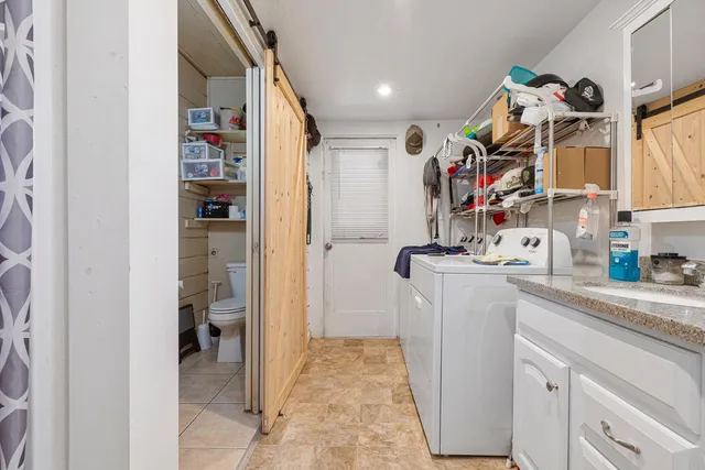 a utility room with stainless steel appliances granite countertop a sink and cabinets