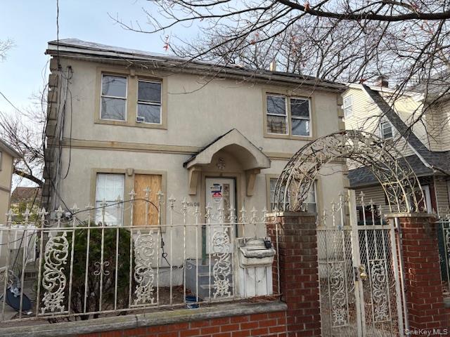 View of front facade with stucco siding, a fenced front yard, and a gate