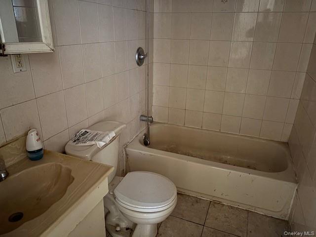 114-06 167th Street Queens, NY 11434 - Photo 21 of 23 Bathroom with tile walls, vanity, washtub / shower combination, and tile patterned floors