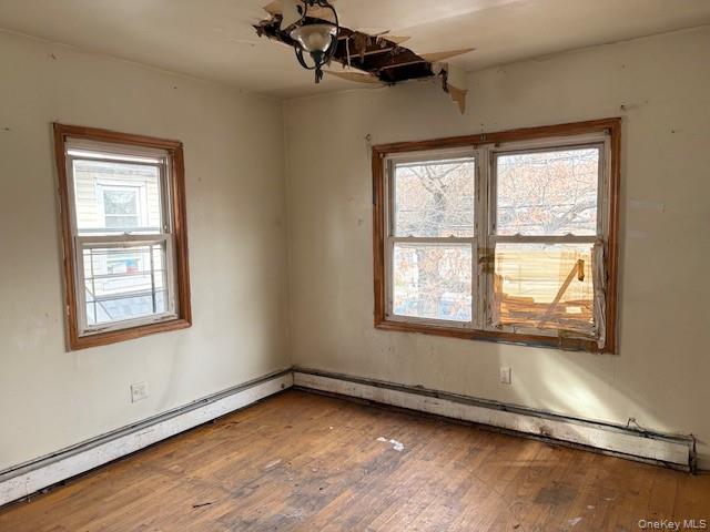 114-06 167th Street Queens, NY 11434 - Photo 8 of 23 Empty room with a baseboard heating unit, wood-type flooring, and plenty of natural light