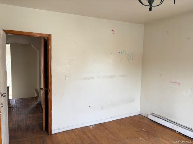 114-06 167th Street Queens, NY 11434 - Photo 9 of 23 Unfurnished room featuring a baseboard heating unit and hardwood / wood-style floors