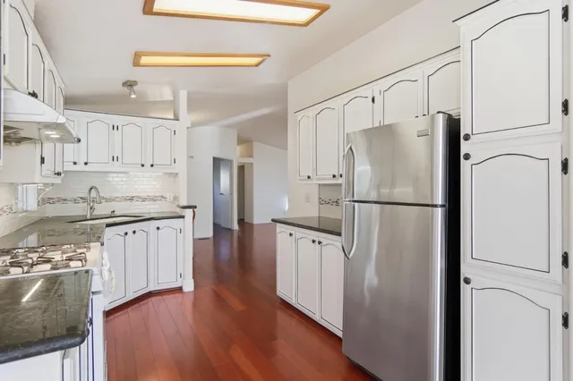 a kitchen with stainless steel appliances granite countertop a refrigerator stove microwave and cabinets