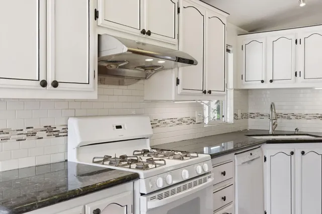 a kitchen with stainless steel appliances granite countertop a sink stove and cabinets