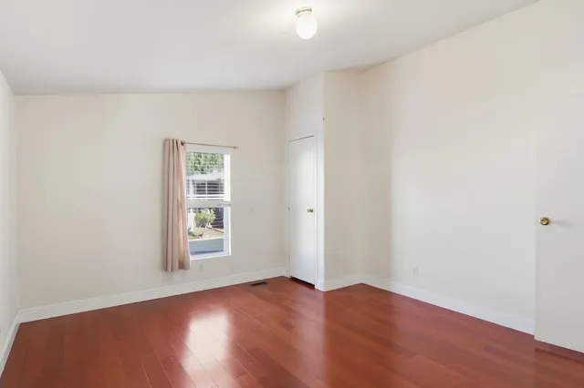 an empty room with wooden floor and window