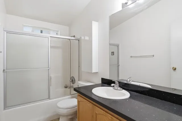 a bathroom with a granite countertop sink toilet a mirror and shower