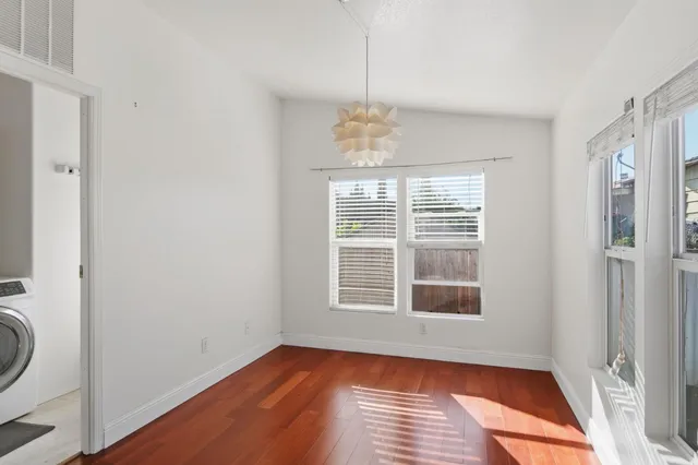 a view of an empty room with a window and wooden floor