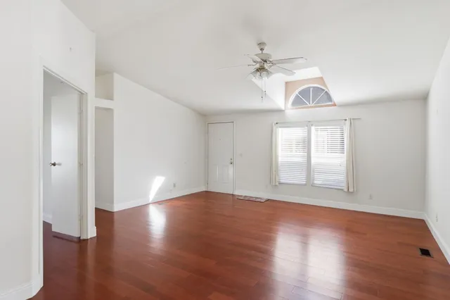a view of an empty room with wooden floor and a window