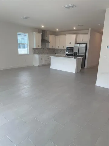 a view of kitchen with kitchen island white cabinets and refrigerator