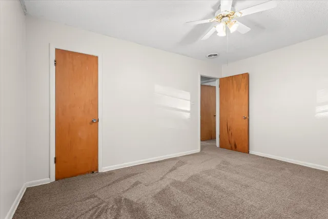 an empty room with windows and fan