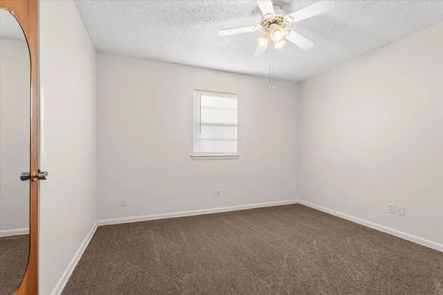 an empty room with a window and a fan